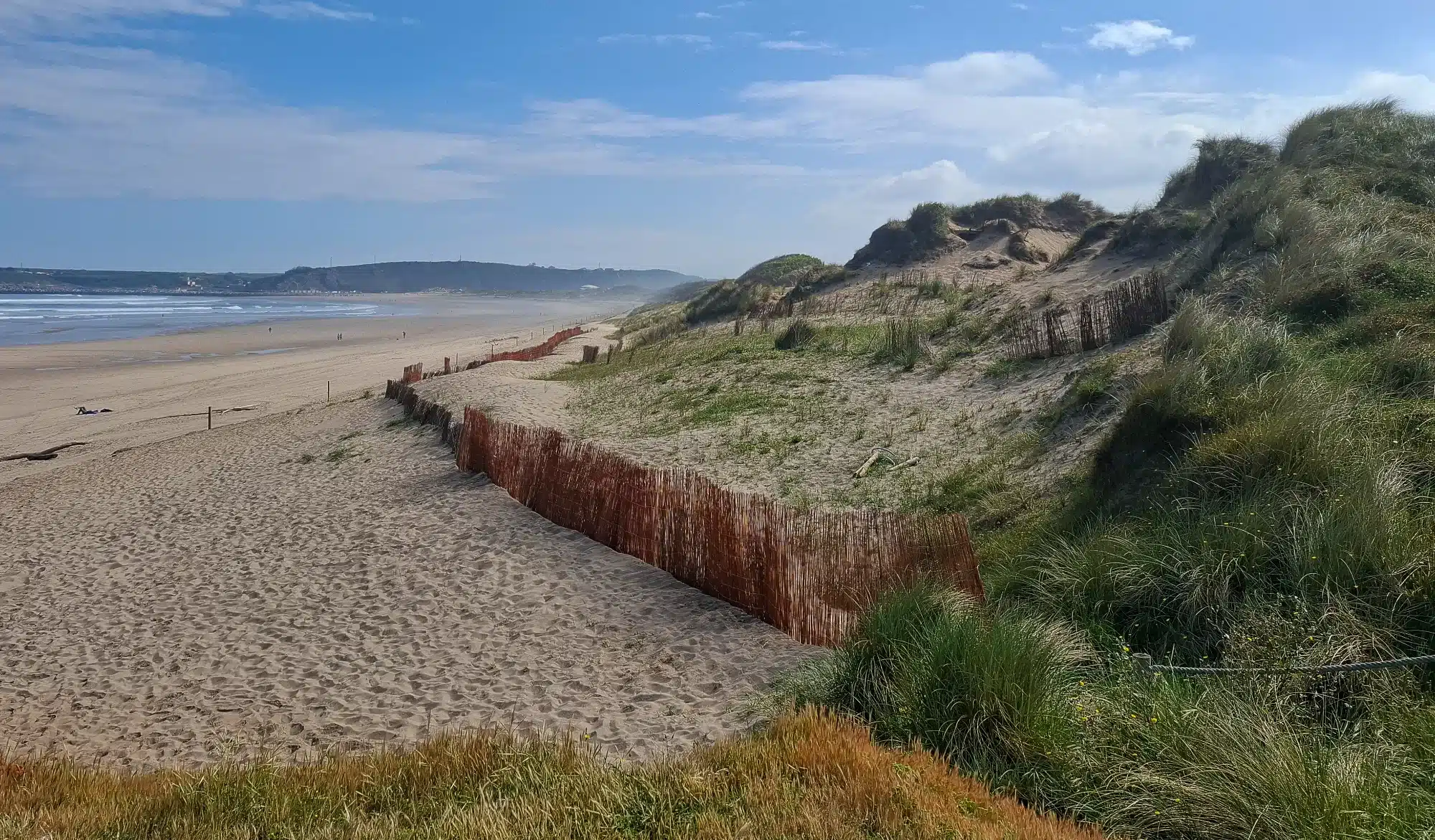 Photo of a beach with dunes and a wooden fence in the sand